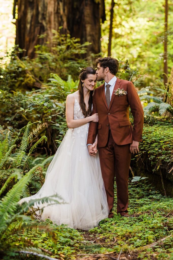 Groom kisses bride on the forehead during redwoods elopement photos on the Oregon Coast