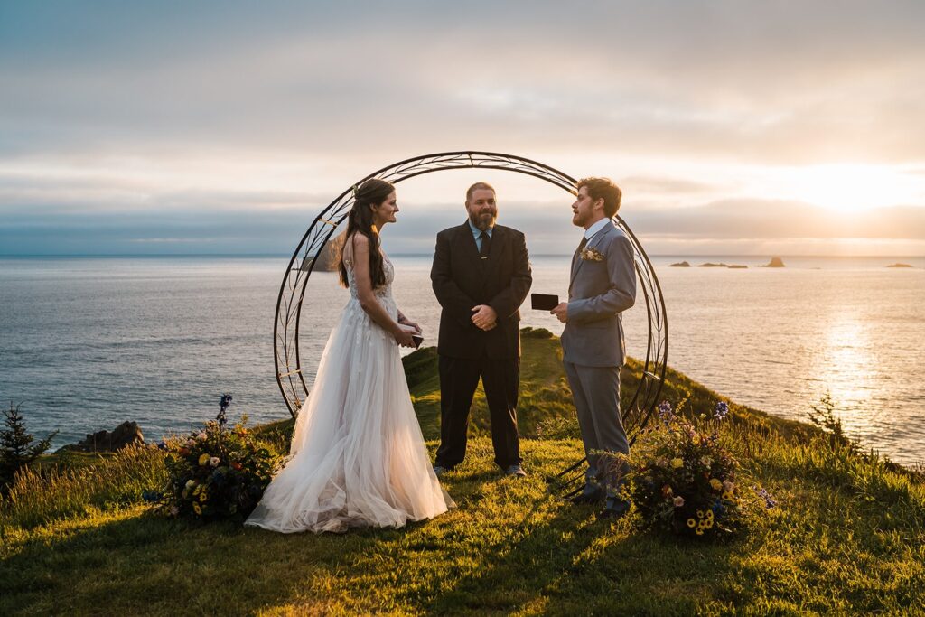 Bride and groom exchange vows on a cliff at sunset on the Oregon Coast