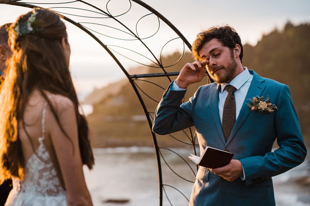 Groom wipes tears from his eyes during sunset elopement ceremony on the Oregon Coast