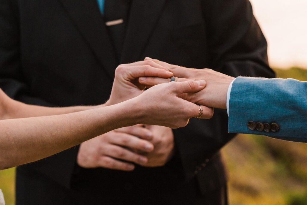 Bride puts black wedding band on groom's hand during Crook Point elopement ceremony