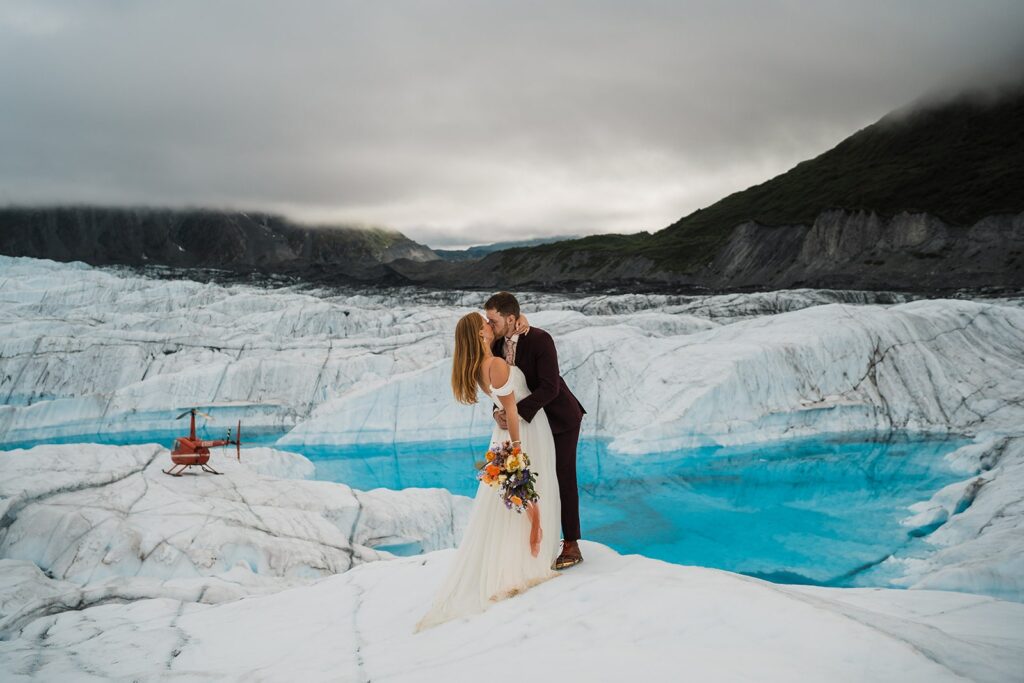 Bride and groom kiss on an ice glacier during their helicopter elopement in Alaska
