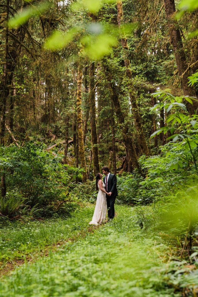 Bride and groom hold hands in the forest during their Oregon Coast elopement photos