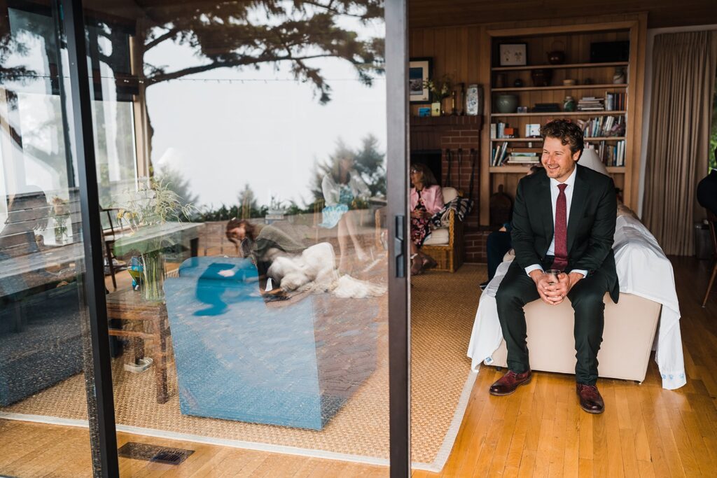 Groom watches as bride plays with dog on the deck of Airbnb cabin