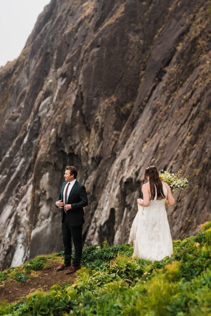 Bride and groom stand on a cliff overlooking the ocean at their Oregon Coast elopement 