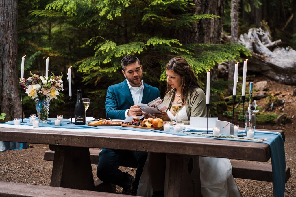 Bride and groom read letters during their elopement in the forest