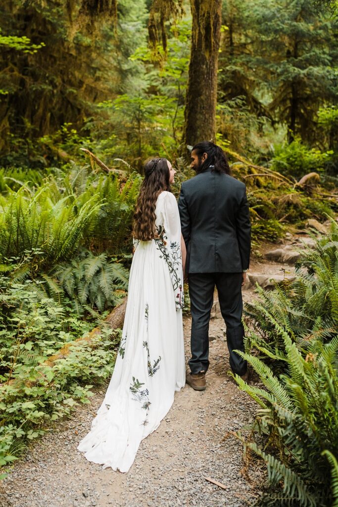 Bride and groom walk through a trail in Hoh Rainforest after their wedding first look 