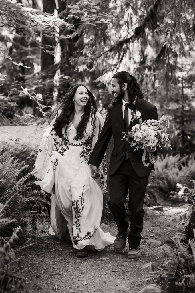 Bride and groom laugh while running through the forest at their Hoh Rainforest wedding
