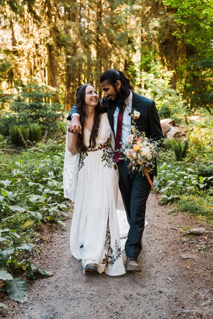 Bride and groom walk arm in arm through the Hoh Rainforest