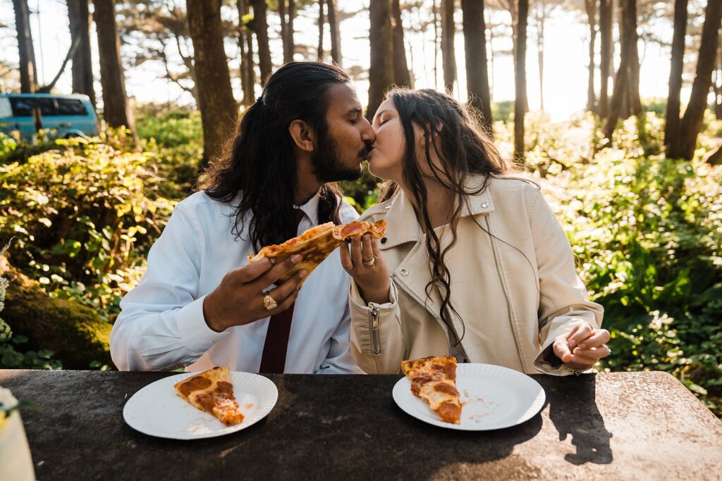 Bride and groom kiss while eating pizza after their Hoh Rainforest wedding ceremony
