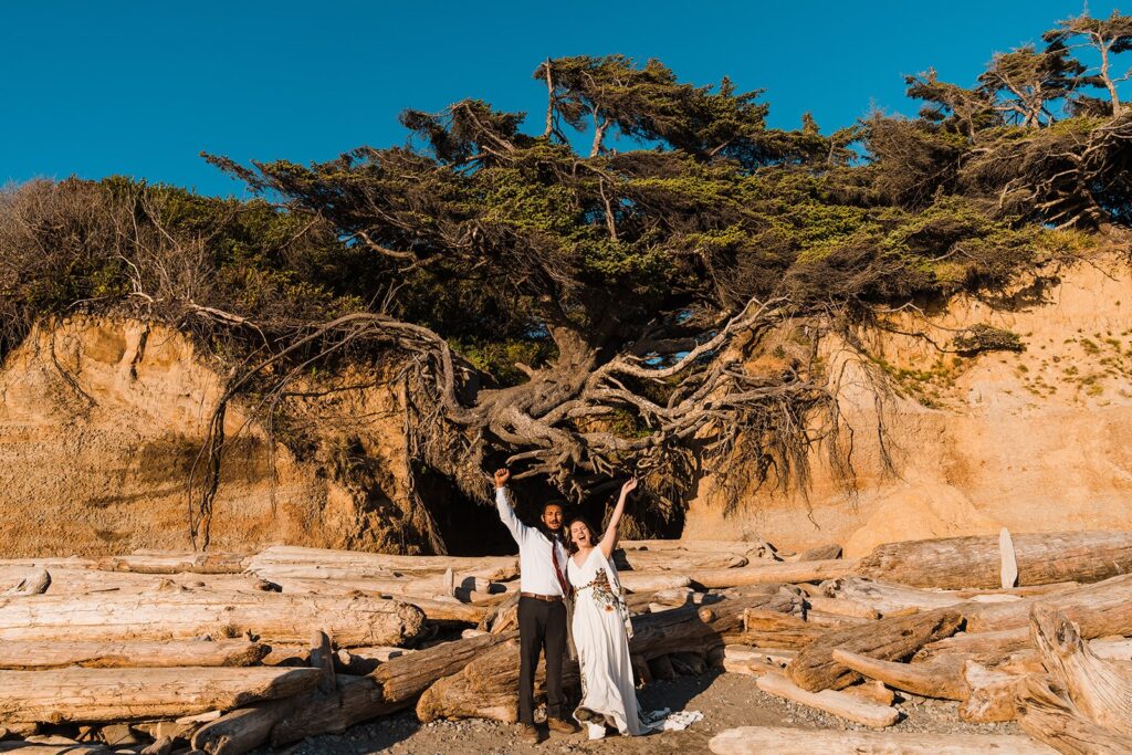 Bride and groom cheer on a beach in the Olympic Peninsula during their Hoh Rainforest wedding photos