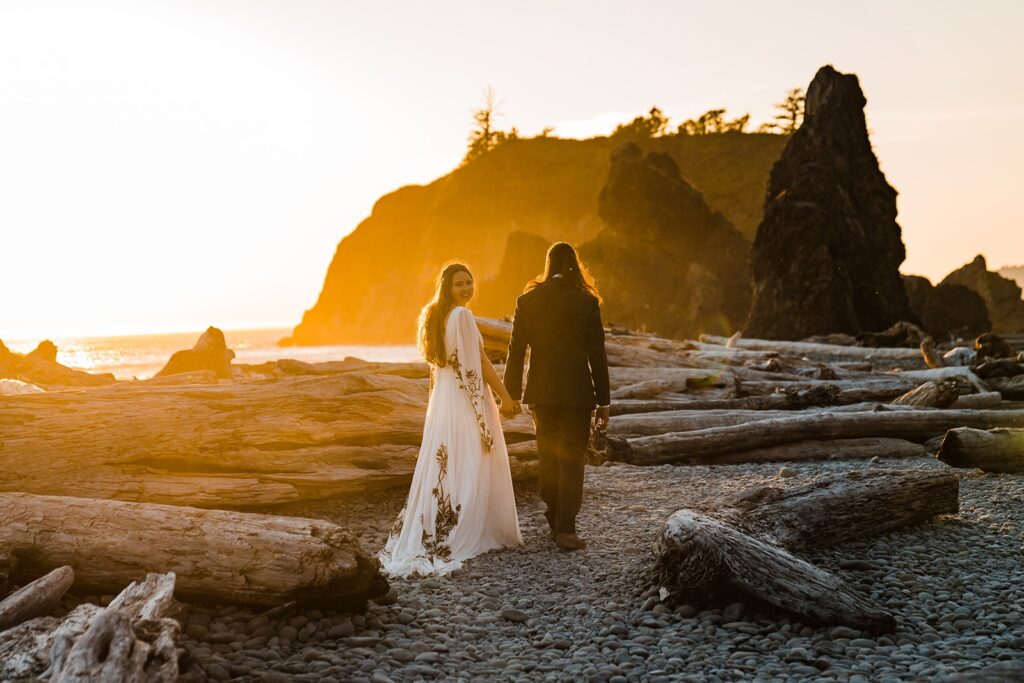 Bride and groom hold hands while walking across Ruby Beach after their Hoh Rainforest wedding
