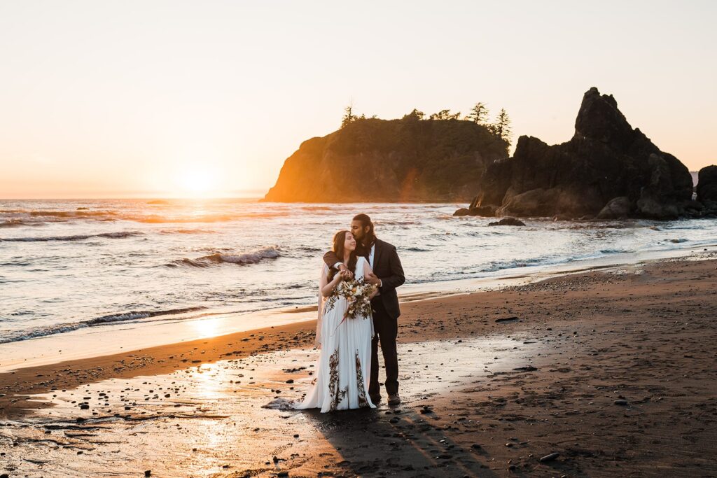 Groom kisses bride on the forehead during sunset wedding photos at Ruby Beach