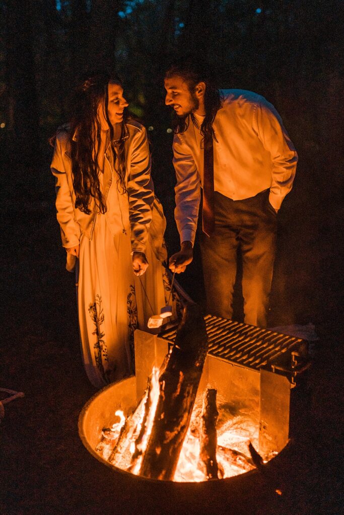 Bride and groom roast s'mores over the fire after their Hoh Rainforest wedding