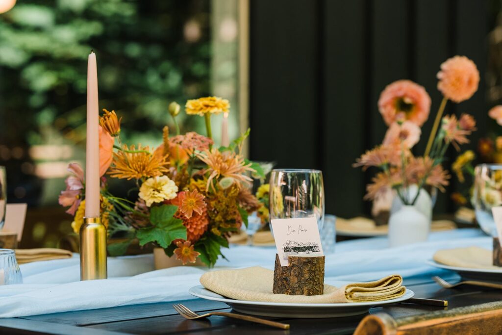 Peach, orange, and yellow flowers and table decorations for Airbnb cabin wedding reception