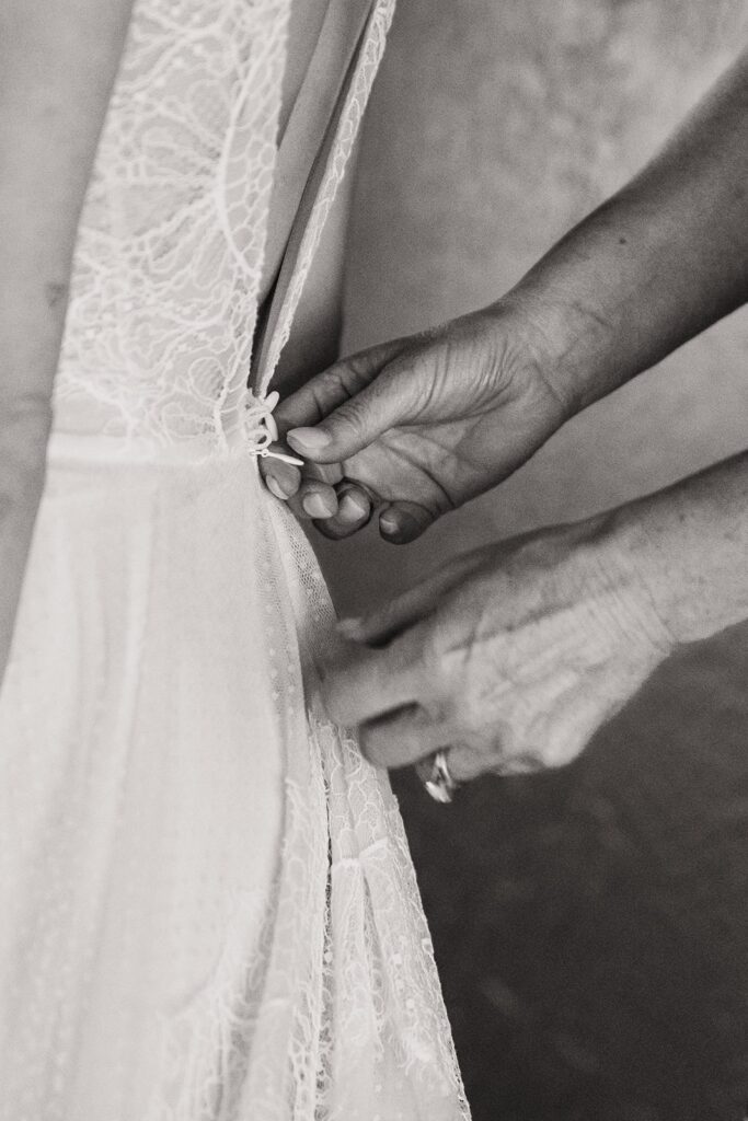 Bride getting zipped into her wedding dress while getting ready for Olympic National Park wedding