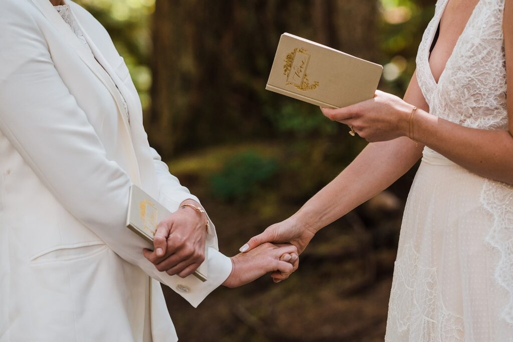 Brides hold hands while exchanging vows at their Olympic National Park wedding
