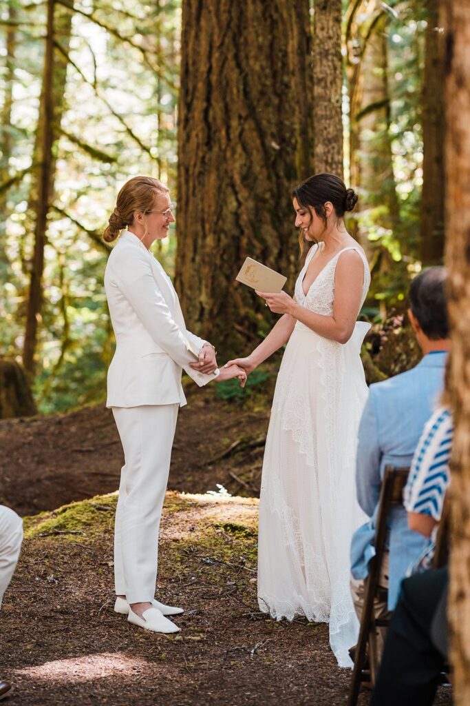 Brides hold hands while exchanging vows at their Olympic National Park wedding