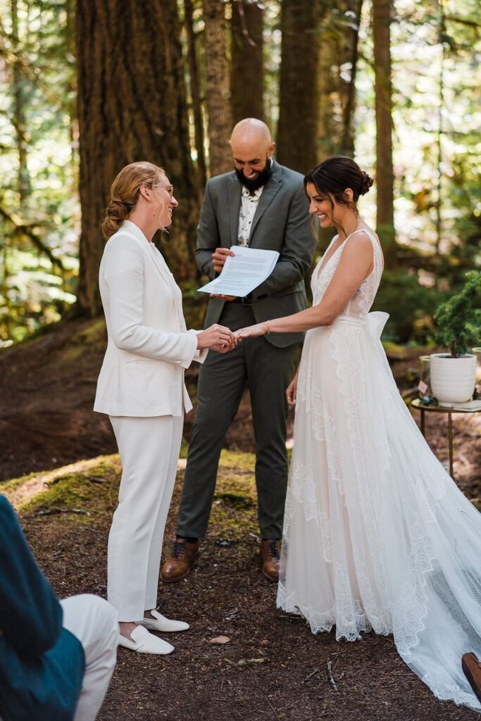 Brides laugh while exchanging rings at their forest wedding in Olympic National Park