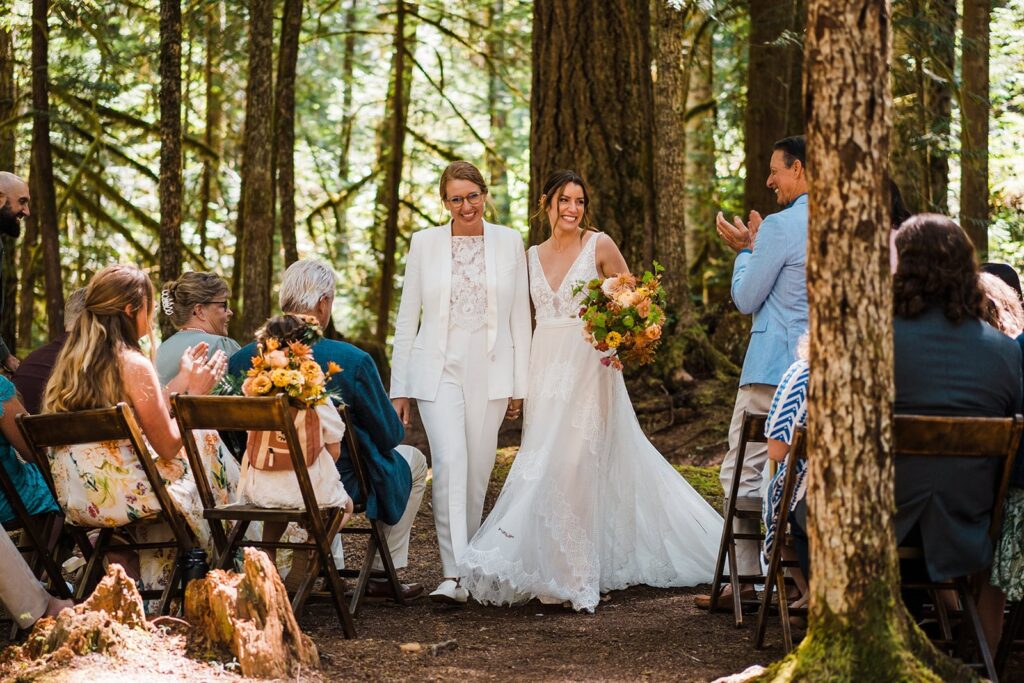 Brides smile while exiting their forest wedding ceremony in Olympic National Park