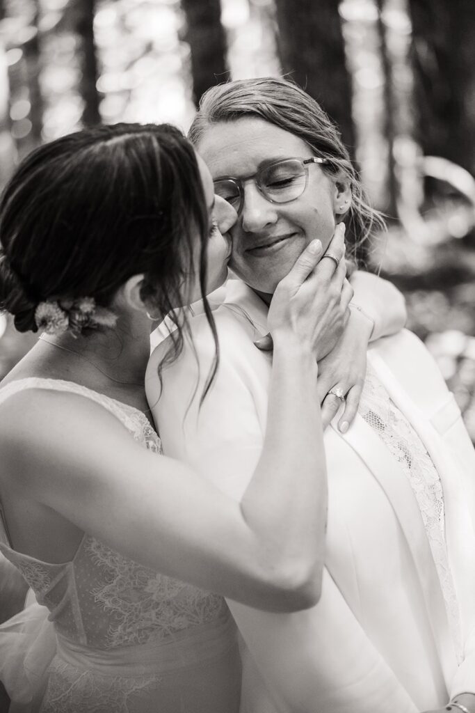 Brides kiss during wedding photos in the forest in Olympic National Park