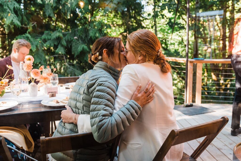 Brides kiss during wedding reception at their Airbnb cabin