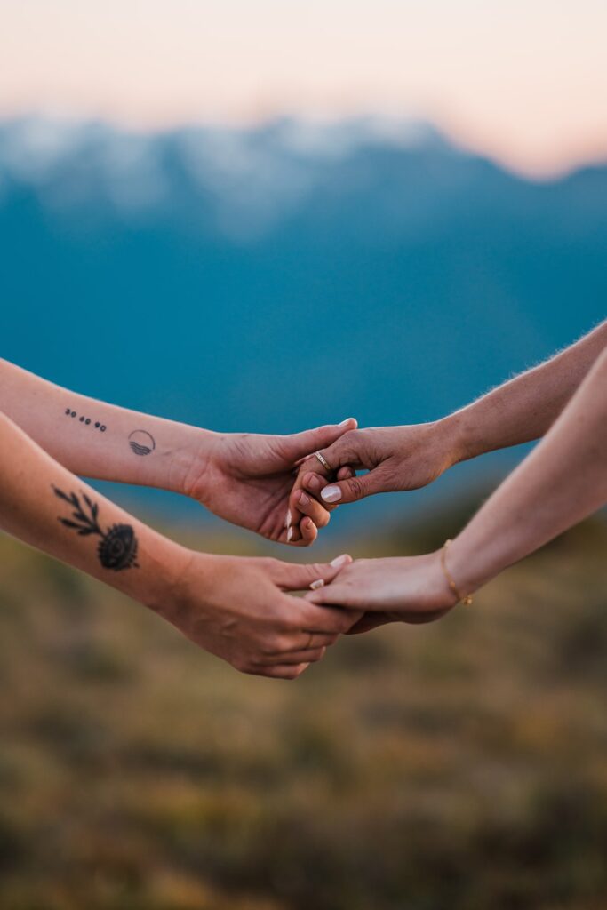 Brides hold hands during their sunset wedding photos in Olympic National Park 