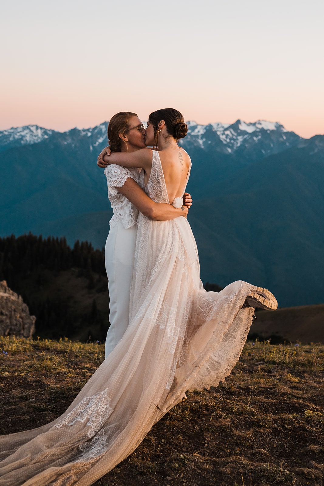 Two brides kiss on a mountain trail during their micro wedding in Olympic National Park