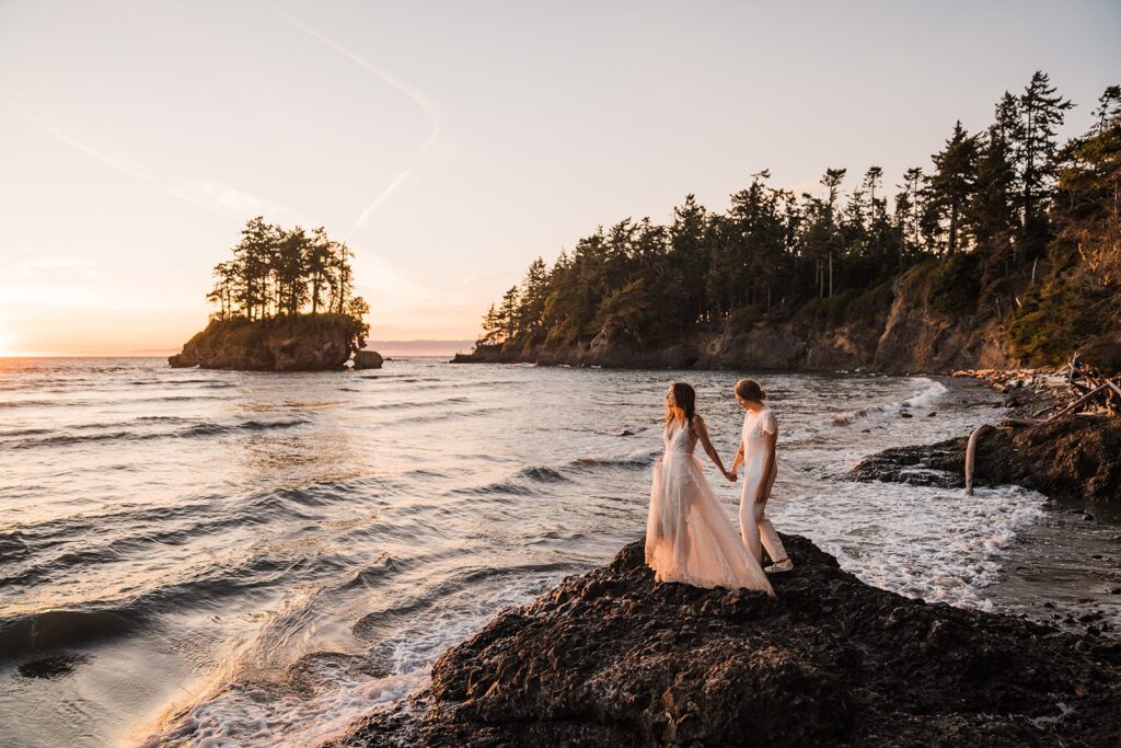 Brides hold hands while looking out at the ocean during their Olympic National Park wedding