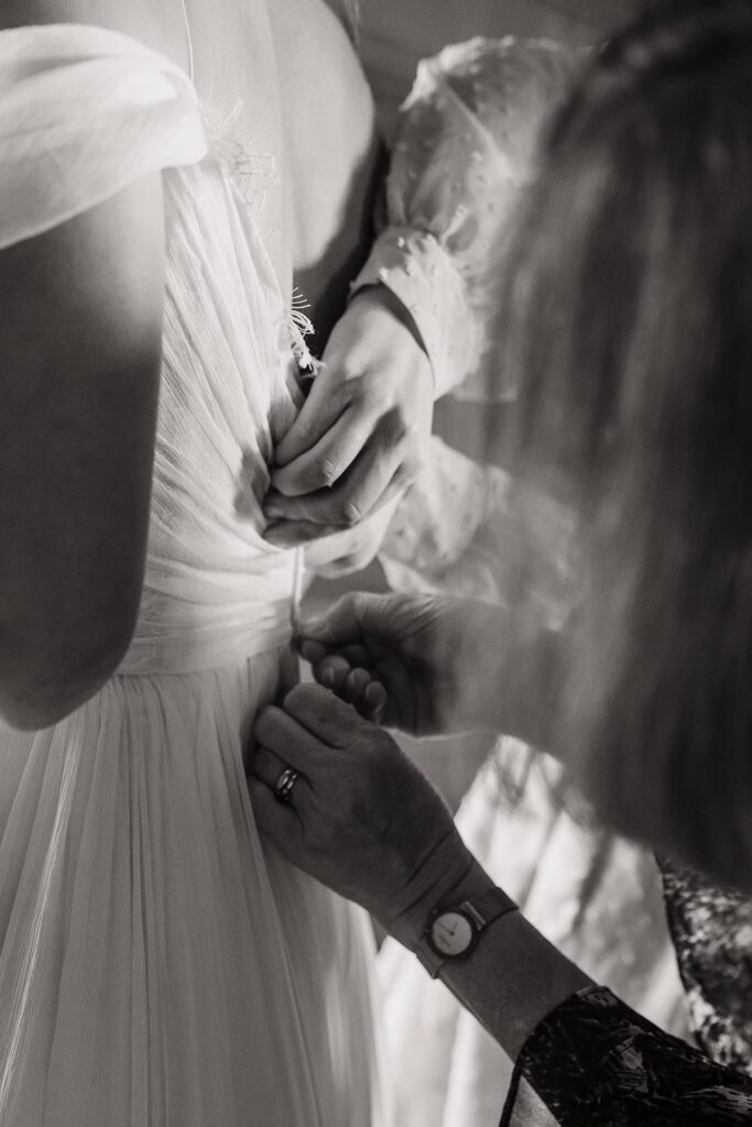 Bride getting zipped into white tulle wedding dress before Alaska elopement