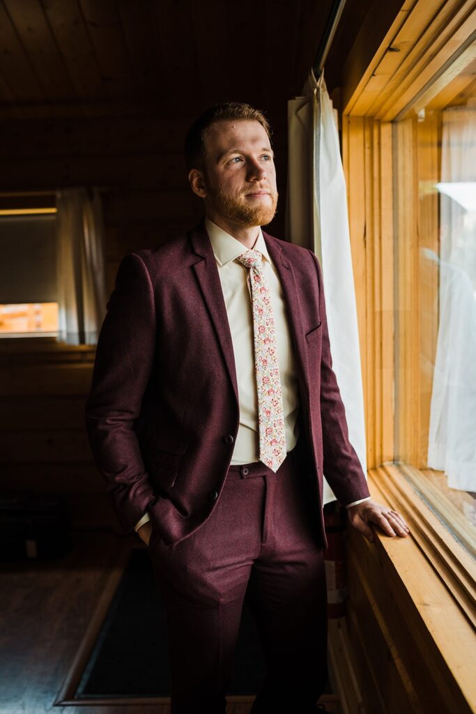 Groom in burgundy suit with cream dress shirt