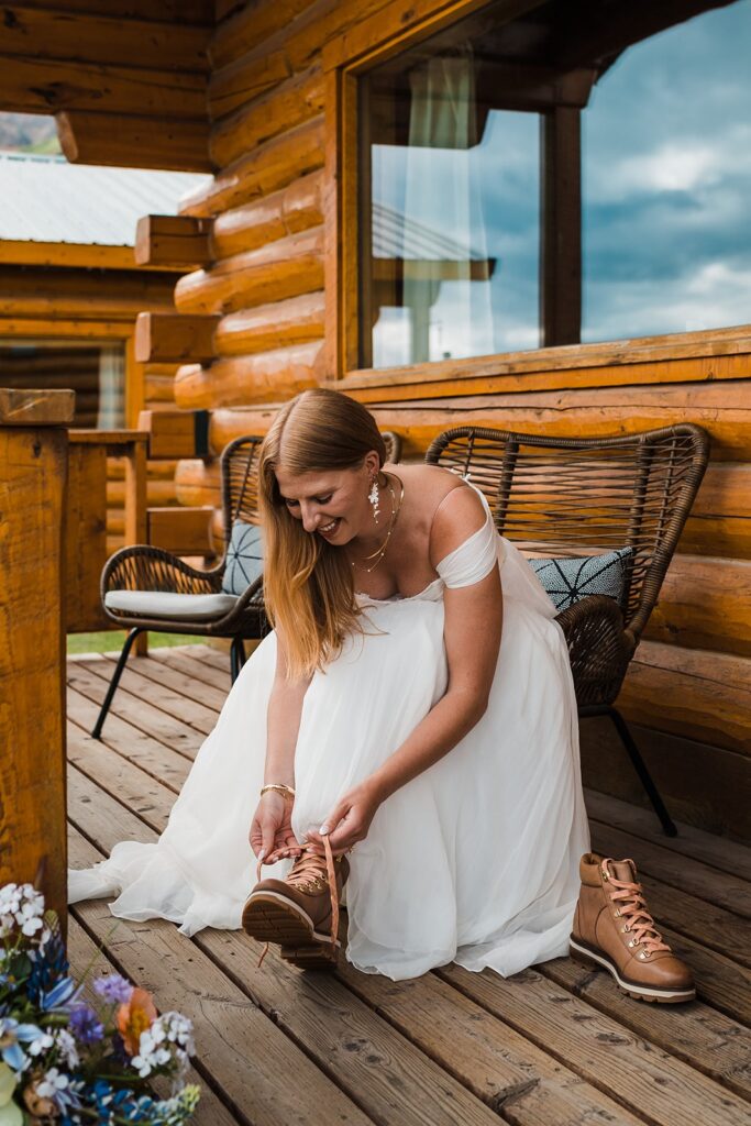 Bride lacing up hiking boots for Alaska elopement