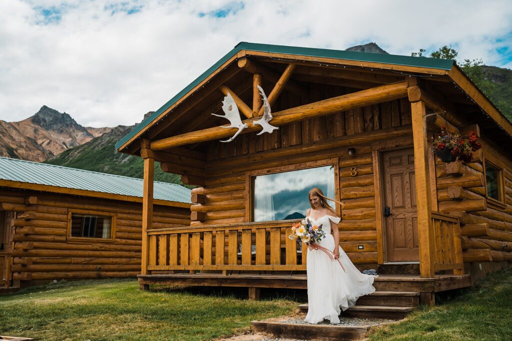 Bride walking down the steps of mountain cabin in Alaska