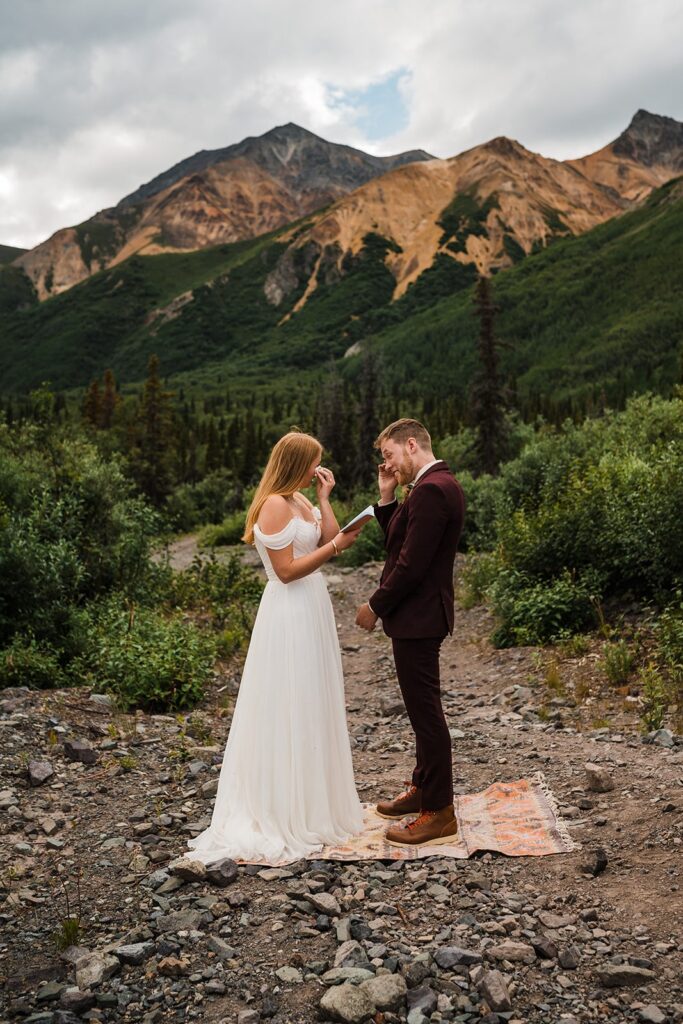 Bride and groom wipe tears during Alaska elopement