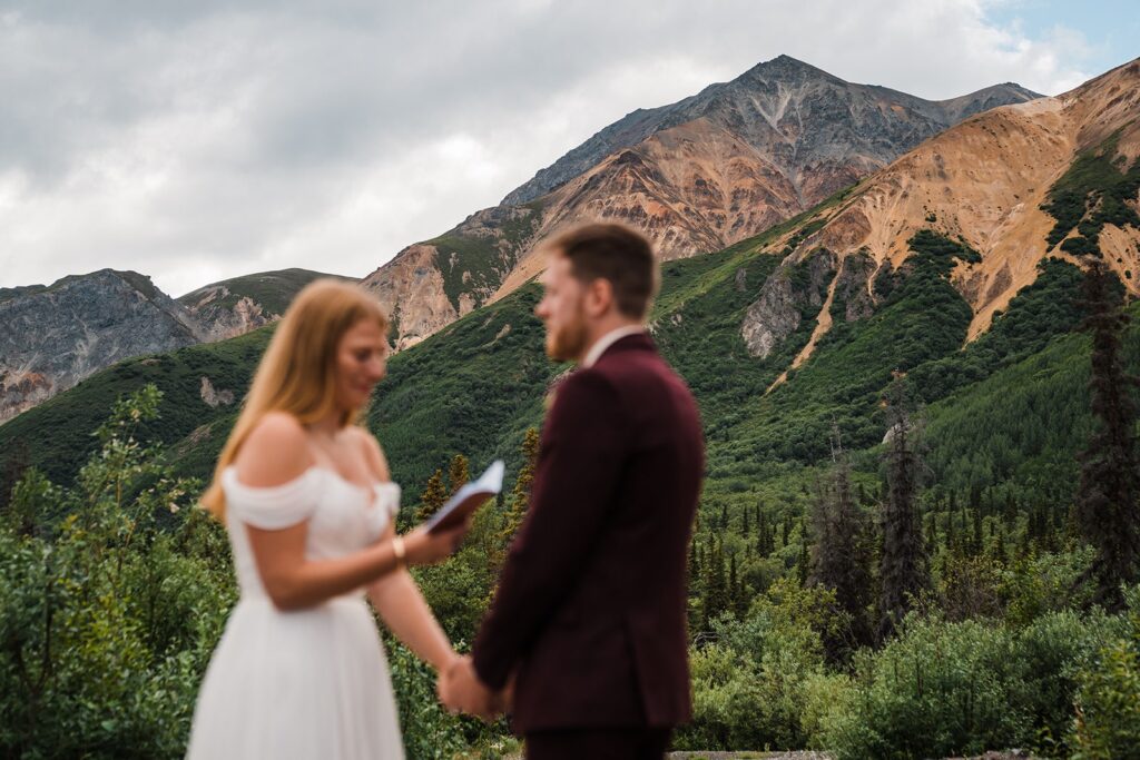 Bride and groom hold hands during elopement ceremony in Alaska