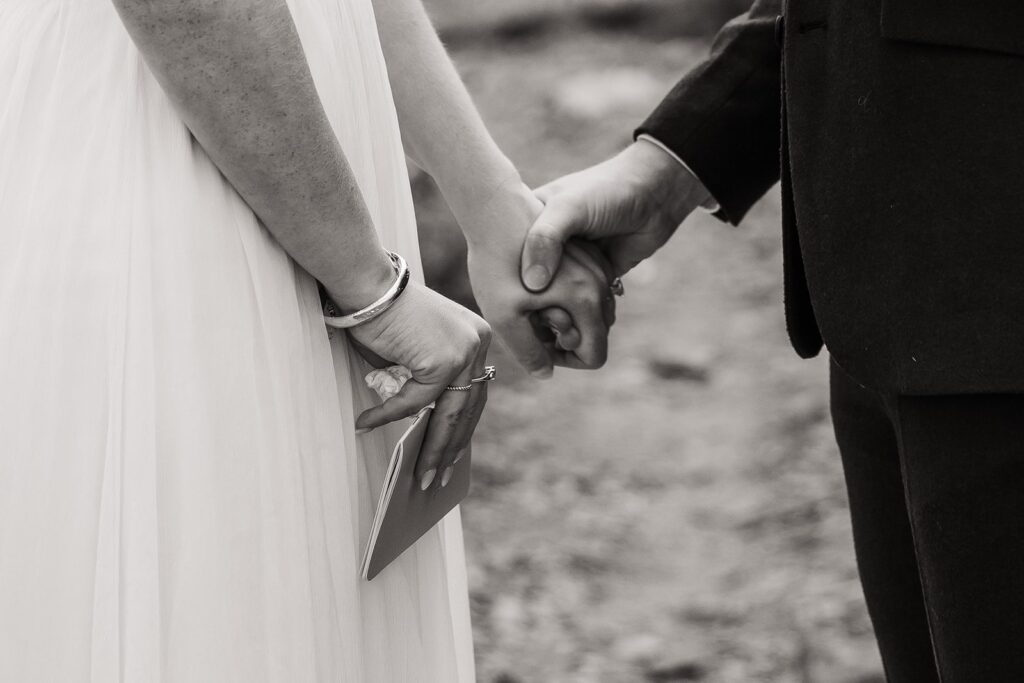 Groom holds bride's hand during elopement ceremony in Alaska