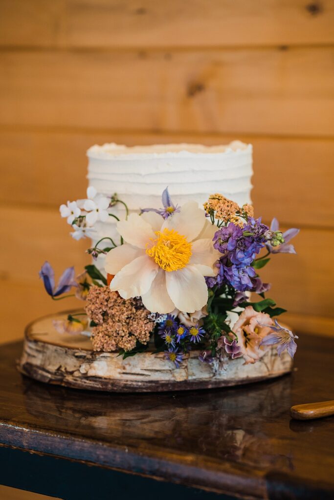 White frosted wedding cake decorated with colorful wildflowers