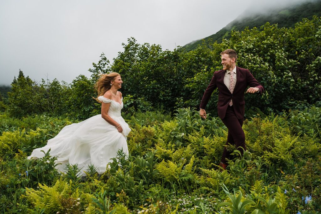 Bride and groom run through the green trails during their adventure elopement in Alaska