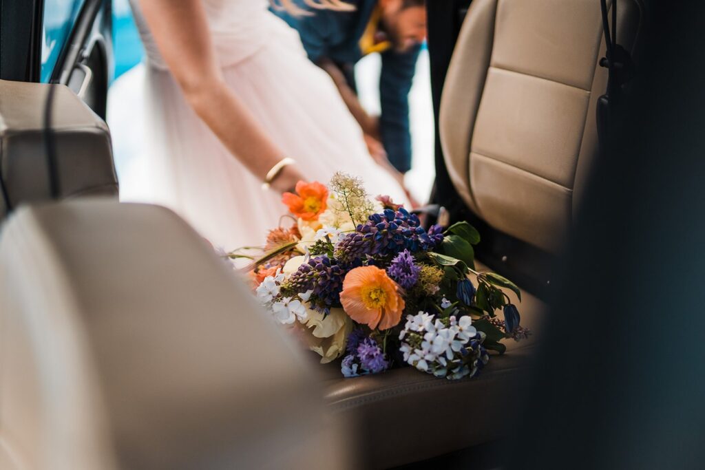Colorful wildflower bouquet sits on the seat of a helicopter during an Alaska elopement