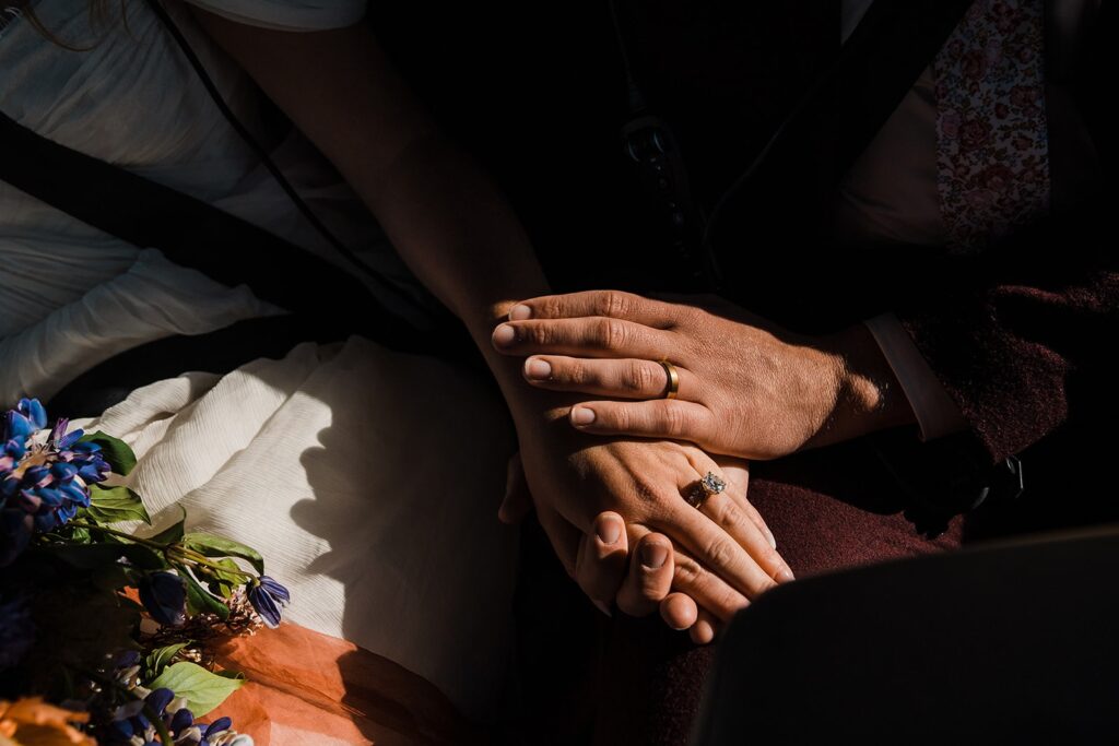 Bride and groom hold hands during their helicopter ride at their elopement in Alaska