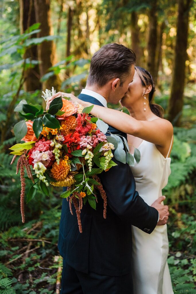Bride and groom kiss in the forest during their summer North Cascades elopement