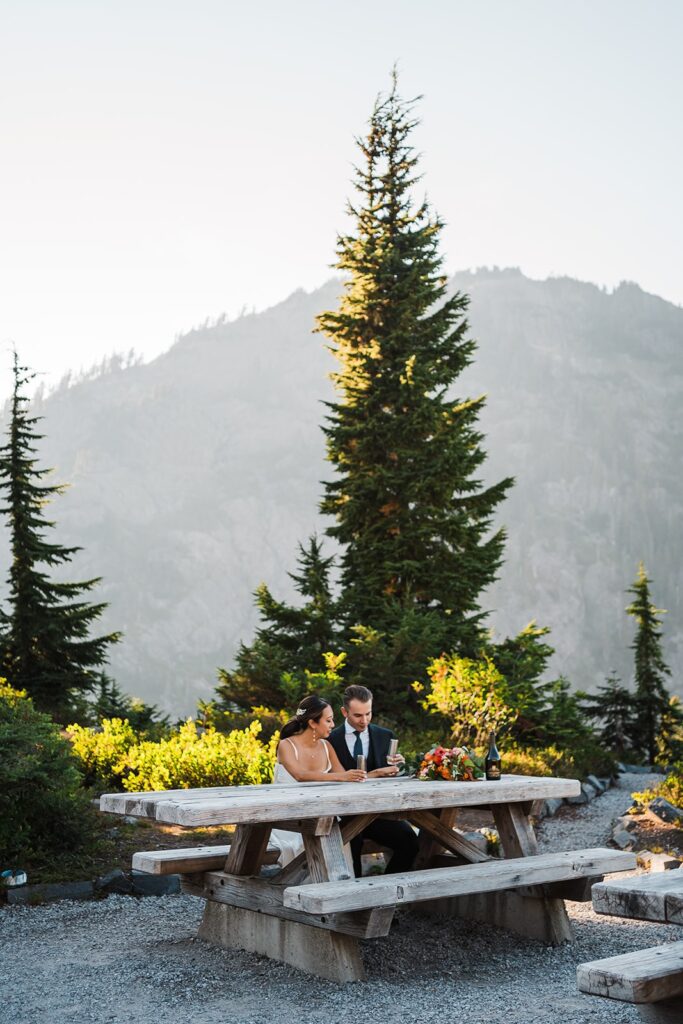 Bride and groom enjoy an elopement picnic at an alpine lake during their North Cascades elopement