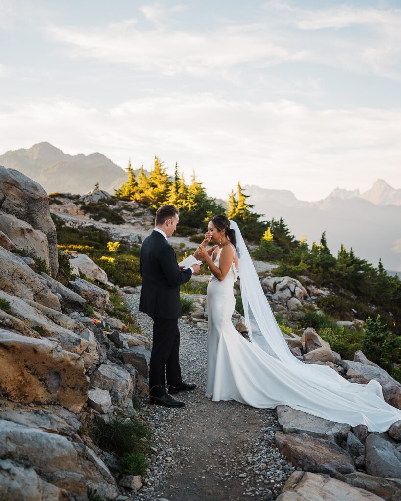 Bride wipes tears while groom reads personal vows at their Artist Point elopement