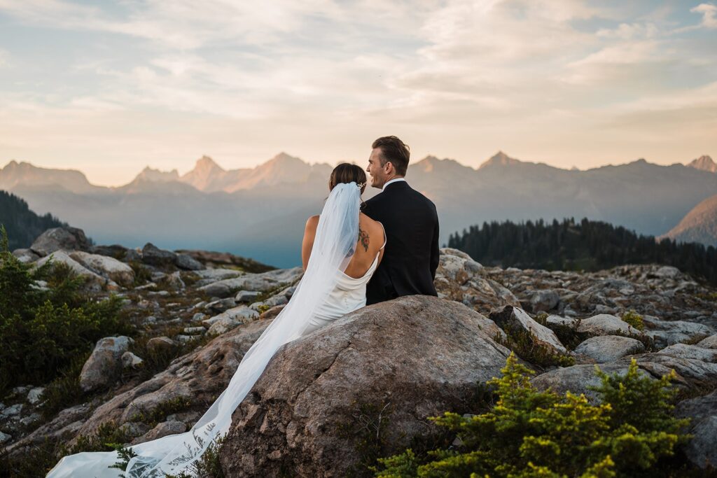 Bride and groom sit on a rock during their Artist Point sunset elopement photos