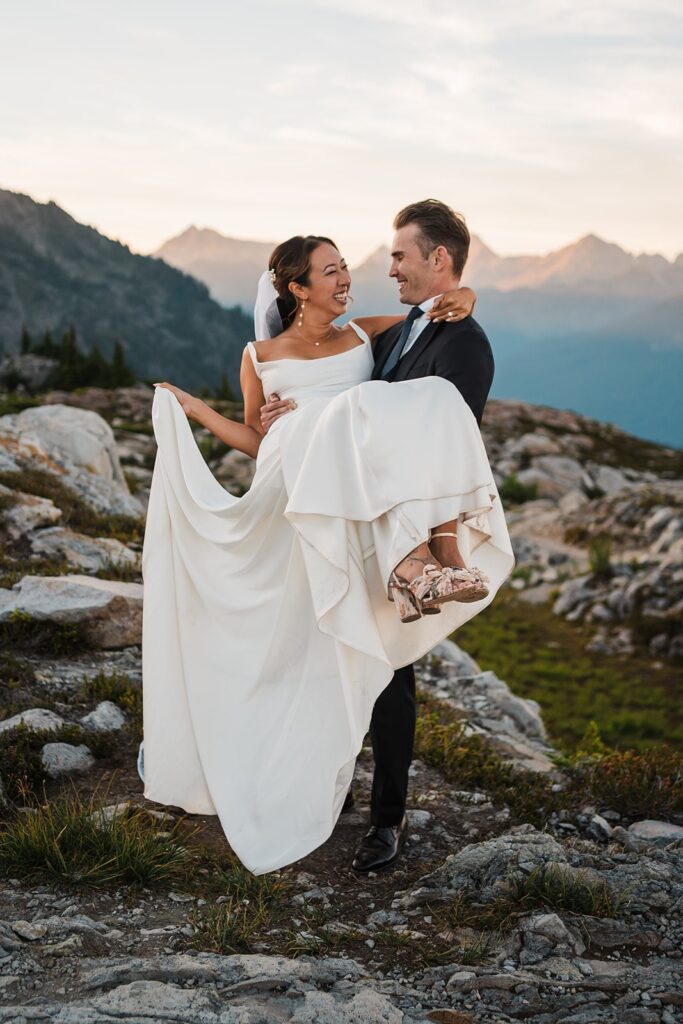 Groom carries bride across a hiking trail during their Artist Point elopement photos