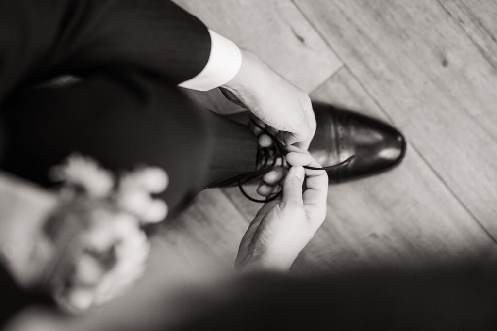 Groom leans over to tie his shoe while getting ready for his Mount Rainier wedding