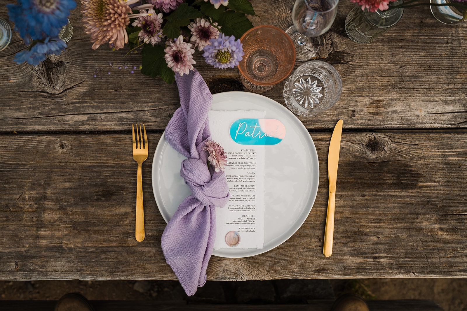 Purple napkin sits atop a white plate with gold silverware at an outdoor Washington elopement reception.