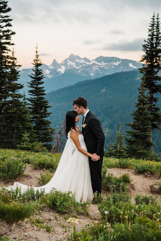 Bride and groom kiss on a hiking trail during their Mount Rainier sunset photos