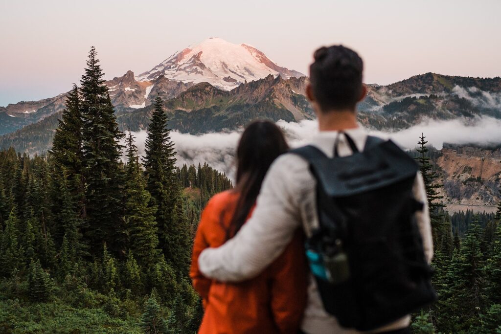 Bride and groom hug during their sunrise elopement photos looking over Mt Rainier