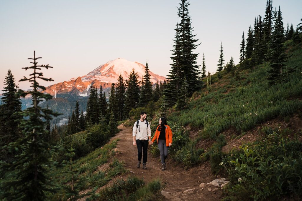 Bride and groom hold hands while hiking to their alpine lake elopement at Mt Rainier