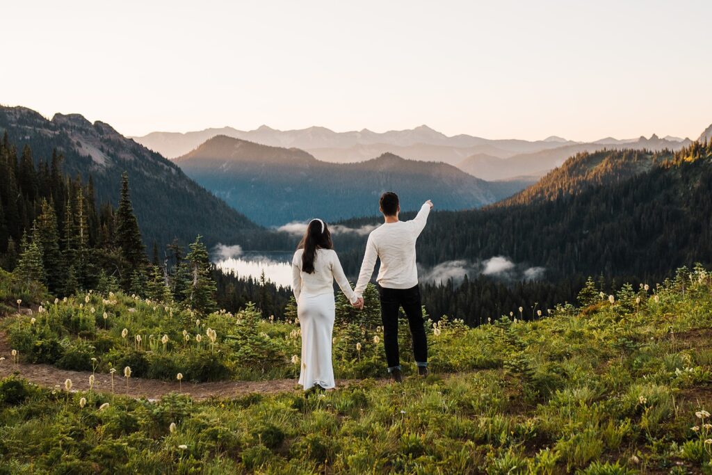 Bride and groom look out over an alpine lake during their sunrise elopement in Washington